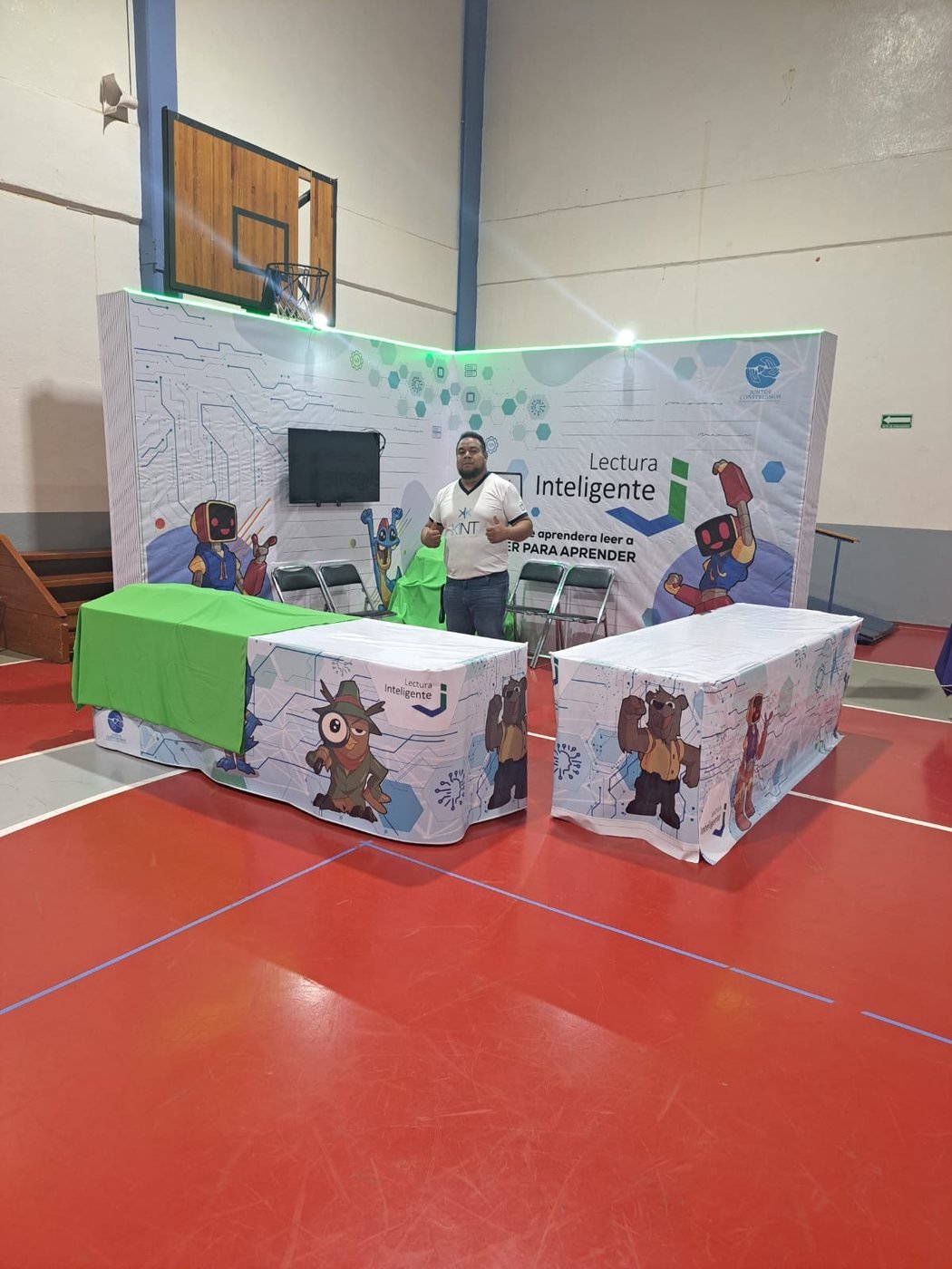 Stand con mesas personalizadas y backdrop de mascotas del programa Lectura Inteligente